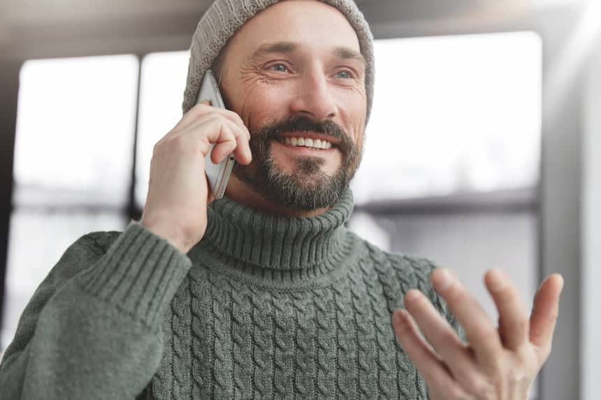 Bel homme barbu souriant, au téléphone