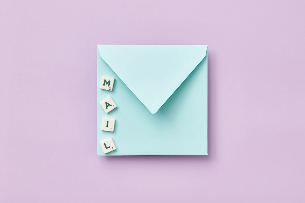Lettre bleue sur fond rose avec des lettres de Scrabble posées dessus formant le mot MAIL